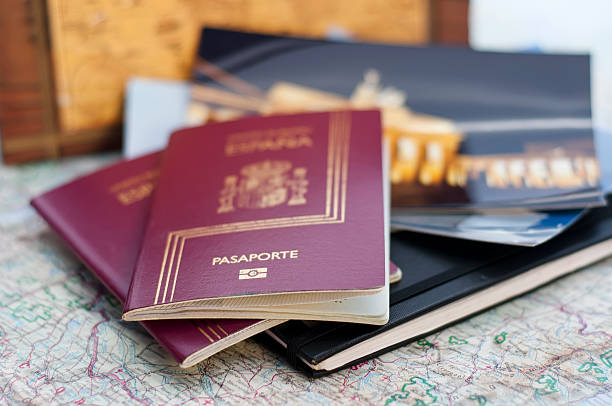 Pasaportes españoles encima de libretas, fotos de viajes y un mapa